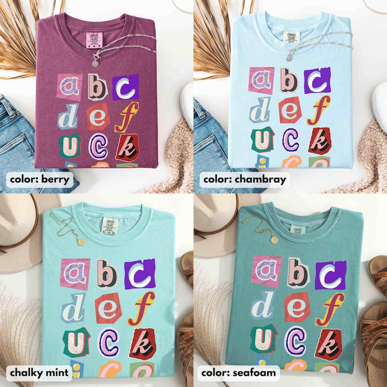May include: Four t-shirts in berry, chambray, chalky mint, and seafoam colours. Each shirt features the letters "abc def Uck" in a colourful, cut-out style design. The shirts are displayed with accessories.