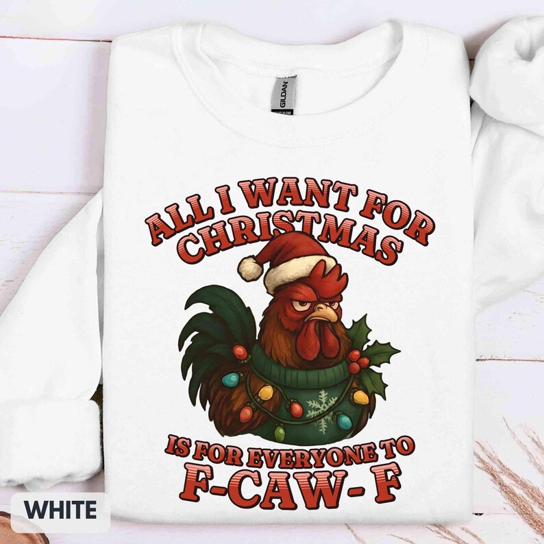 May include: White sweatshirt with a humorous Christmas graphic. The design features a grumpy rooster wearing a Santa hat and a sweater, surrounded by Christmas lights and holly. Text reads "ALL I WANT FOR CHRISTMAS IS FOR EVERYONE TO F-CAW-F."