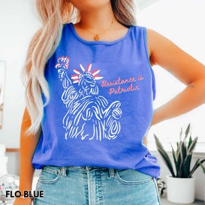Pu&ograve; includere: Una canotta blu con un'illustrazione bianca della Statua della Libert&agrave; che tiene una torcia, con la scritta rossa "Resistance is Patriotic". La canotta &egrave; realizzata in un materiale morbido ed &egrave; di una tonalit&agrave; blu vibrante.