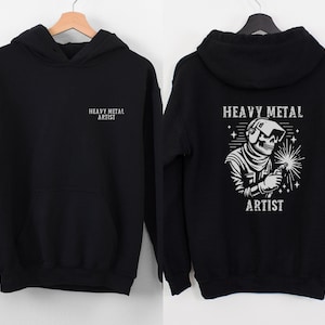 May include: Black hoodie with a white graphic of a skeleton welding with the text "Heavy Metal Artist" on the back and "Heavy Metal Artist" on the front.