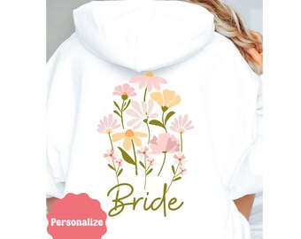 May include: White hoodie with a floral design and the word "Bride" printed on the back.
