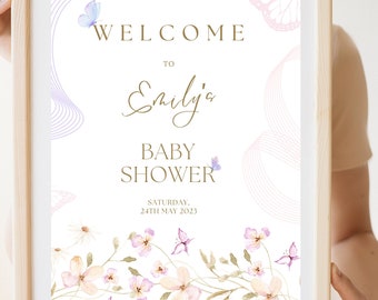 Könnte beinhalten: Willkommen zur Babyparty von Emily Schild mit Blumenmuster und Schmetterlingen. Das Schild ist auf weißem Papier gedruckt und in einem hellen Holzrahmen gerahmt. Der Text auf dem Schild lautet "Willkommen zur Babyparty von Emily, Samstag, 24. Mai 2023."