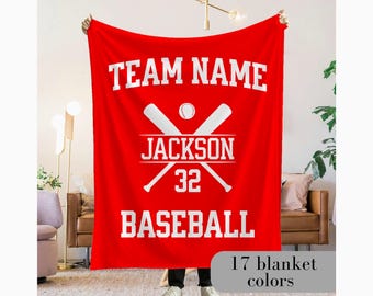 May include: A red baseball blanket with white text and graphics. The blanket features the words "TEAM NAME" at the top, "JACKSON" and the number "32" in the center, and "BASEBALL" at the bottom. Crossed baseball bats and a baseball are also displayed.
