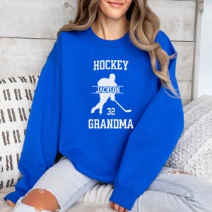 May include: Royal blue sweatshirt with the text "HOCKEY" in white, a silhouette of a hockey player with the text "JACKSON" above and "32 GRANDMA" below.
