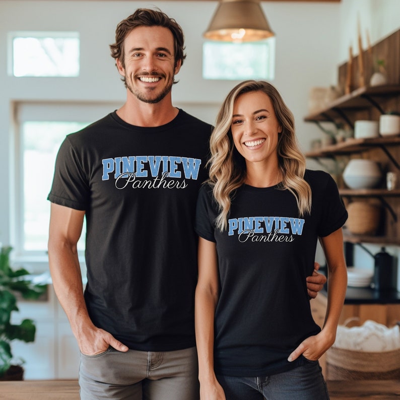 Puede incluir: Dos camisetas negras con el texto "Pineview Panthers" en letras azules. Las camisetas las llevan dos personas de pie en una cocina.
