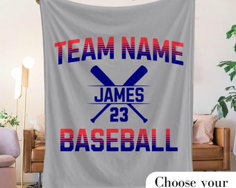May include: Gray fleece blanket with a red, white, and blue baseball theme. The text reads "TEAM NAME JAMES 23 BASEBALL".