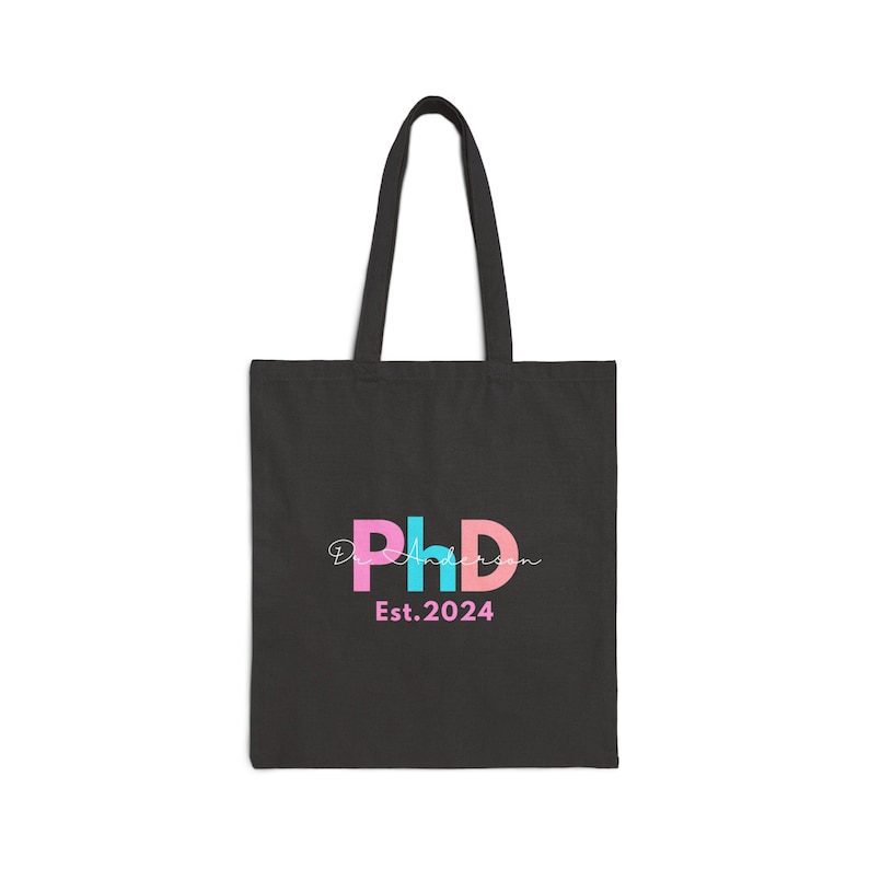 May include: Black tote bag with a pink, blue, and white "PhD" logo and the text "Est. 2024".