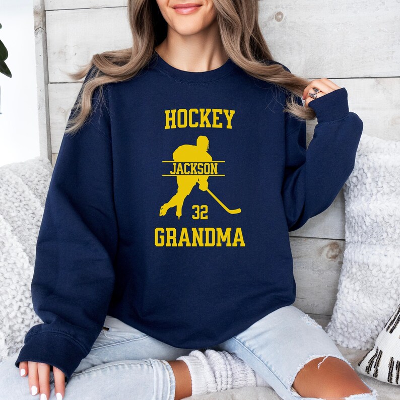 May include: Navy blue sweatshirt with a yellow graphic of a hockey player and the text "HOCKEY JACKSON 32 GRANDMA".