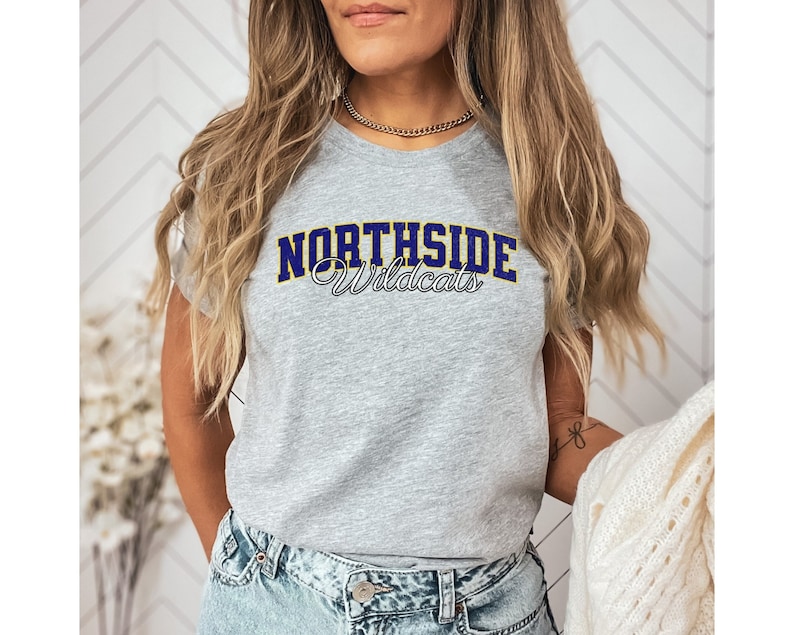Custom school mascot shirt with the school name written in a varsity font in a personalized color and outline, with the mascot written in a classic vintage style script font below it in white with a black outline.
