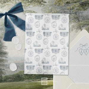 May include: A stationery set featuring a patterned paper with blue illustrations of buildings and crests. A blue ribbon, wax seals, and an envelope with heart-shaped designs and initials complete the elegant presentation. The overall theme is wedding stationery.