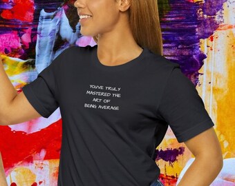 Puede incluir: Dos personas con camisetas negras con texto blanco que dice "You've truly mastered the art of being average". Las camisetas están sobre un fondo abstracto de colores.