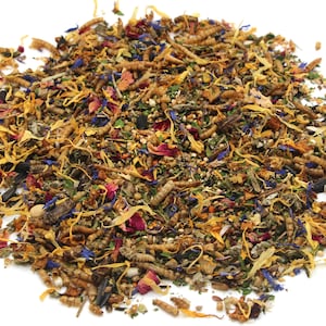 May include: A close-up of a mixture of dried insects, herbs, and flower petals. The mixture is a light brown color with hints of yellow, red, and blue.