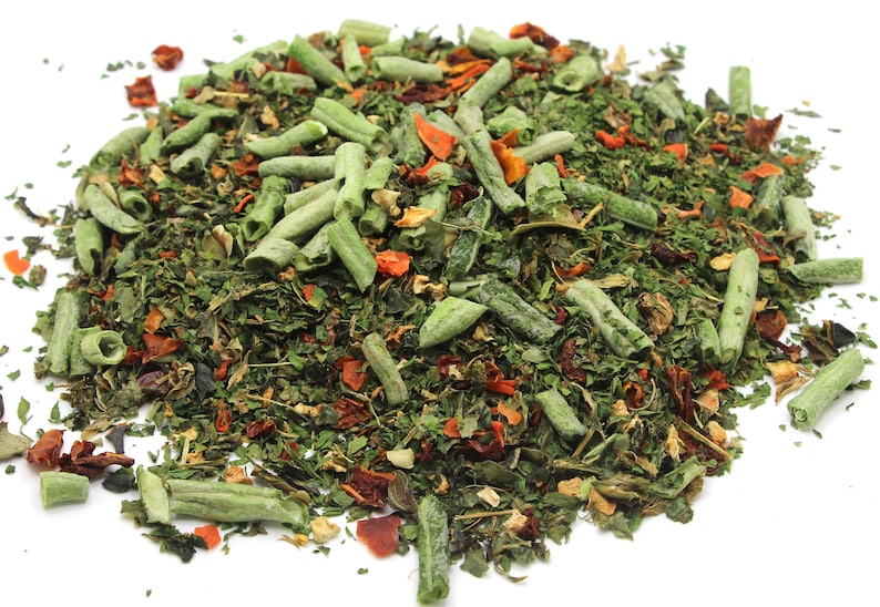 May include: A close-up of a pile of dried herbs and vegetables, including green leafy herbs, long green pieces of dried vegetables, and small orange and red pieces of dried vegetables.