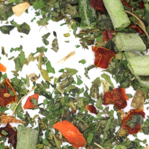 May include: A close-up of a mix of dried herbs and vegetables, including green leafy herbs, red and orange dried peppers, and long green pieces of dried vegetables.