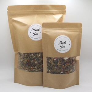 May include: Two brown paper bags with clear windows, each containing a mix of seeds and dried herbs. The bags have white circular labels with the text "Thank You" and "Hamstereatery".