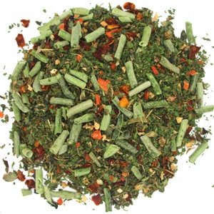 May include: A close-up of a mixture of dried herbs and vegetables, including green herbs, red pepper flakes, and orange carrot pieces.