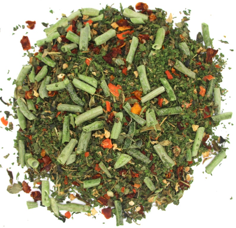 May include: A close-up of a mixture of dried herbs and vegetables, including green herbs, red pepper flakes, and orange carrot pieces.