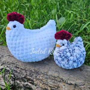 May include: Two crocheted chickens, one white and one blue and white, with burgundy pom-pom hats. The chickens are sitting on a log.