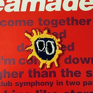 May include: A yellow and red embroidered patch with a black and white face and the text "amade come together I'm co ed down gher than the s dub symphony in two pa shine like stars".