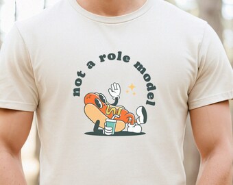 May include: A beige t-shirt with a cartoon hot dog character and the text "not a role model".