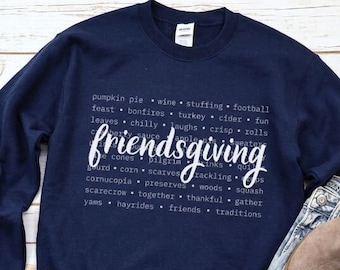 Könnte beinhalten: Marineblaues Friendsgiving-Sweatshirt mit weißem Text. Das Wort "friendsgiving" ist in einer Schreibschrift. Andere Wörter wie "pumpkin pie", "wine", "stuffing" und "football" umgeben das Wort. Das Sweatshirt wird mit Jeans und braunen Stiefeln kombiniert.