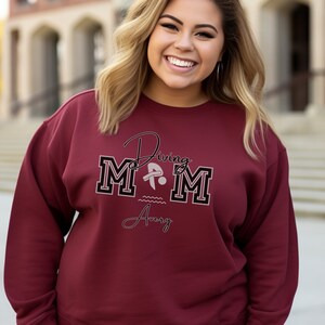 Maroon colored sweatshirt featuring the phrase "Diving Mom " and illustrated with a diver. Includes a place to add your diver's name
