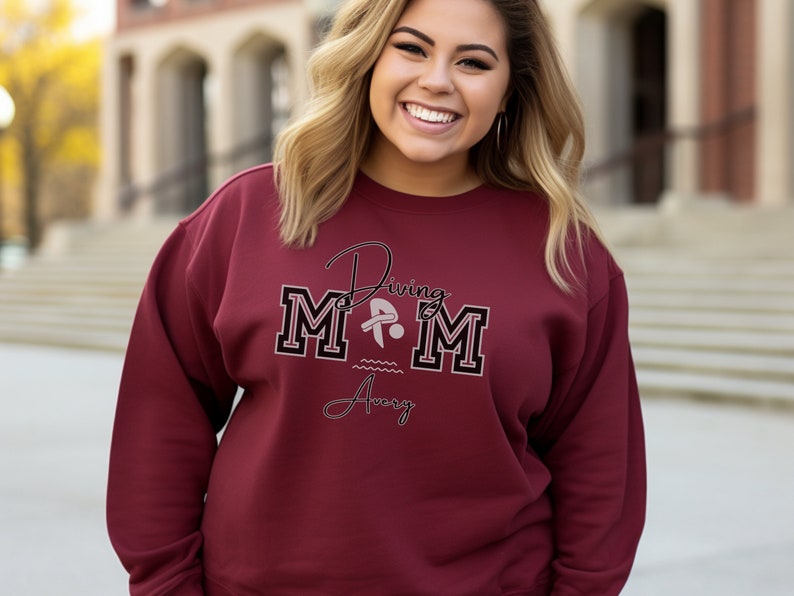 Maroon colored sweatshirt featuring the phrase "Diving Mom " and illustrated with a diver. Includes a place to add your diver's name
