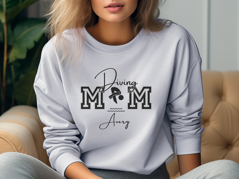 Ash colored sweatshirt featuring the phrase "Diving Mom " and illustrated with a diver. Includes a place to add your diver's name
