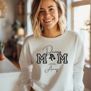 White colored sweatshirt featuring the phrase "Diving Mom " and illustrated with a diver. Includes a place to add your diver's name