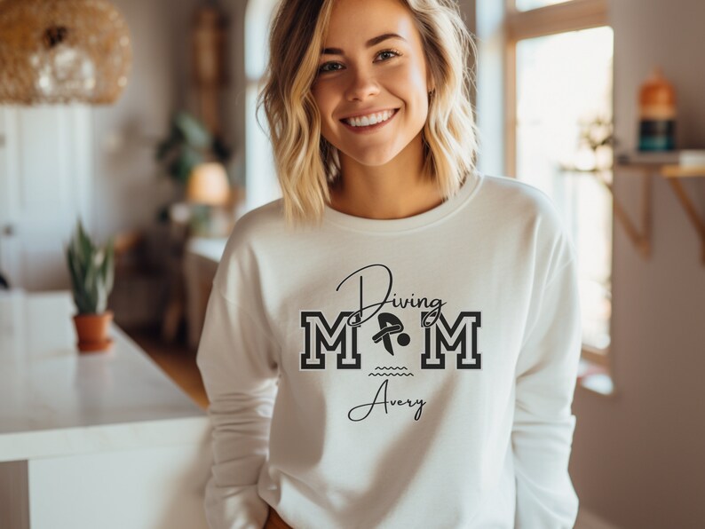 White colored sweatshirt featuring the phrase "Diving Mom " and illustrated with a diver. Includes a place to add your diver's name