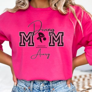 Heliconia (hot pink) colored sweatshirt featuring the phrase "Diving Mom " and illustrated with a diver. Includes a place to add your diver's name
