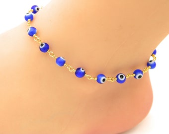 May include: A gold chain anklet with blue evil eye beads. The anklet is a popular charm for protection and good luck.