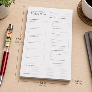 May include: A white notepad for registered dietitians featuring an ADIME note template with sections for nutrition assessment, diagnosis, intervention, and monitoring. The notepad measures 8.5 inches by 5.5 inches by 0.25 inches in total thickness.