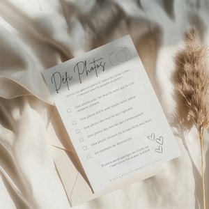 May include: A white card with black text that reads 'Difc Photos' and has a checklist of photo challenges for a wedding. The challenges include taking photos of the couple, the guests, and the wedding decorations. The card also has a small camera icon and two hearts.