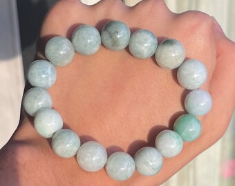 May include: A jade bracelet with light green beads. The bracelet is made of natural jade and has a smooth, polished finish.