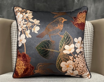 May include: Square decorative pillow with a dark gray background featuring a bird perched on a branch with leaves and flowers. The bird and floral elements are in shades of brown, gold, and white. The pillow has a black border.