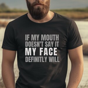Puede incluir: Camiseta negra con el texto "IF MY MOUTH DOESN'T SAY IT MY FACE DEFINITLY WILL" en letras blancas y grises. La camiseta la lleva una persona con barba.