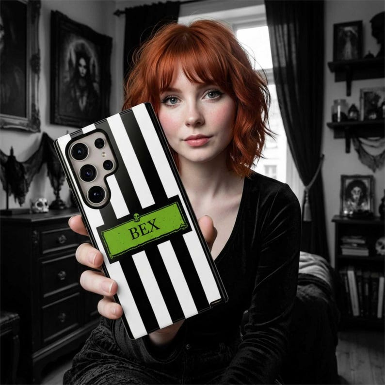 An emo goth woman holding a custom black and white striped phone case with the name 'BEX'. The custom phone case is available for iPhone, Samsung Galaxy and Google Pixel and is a perfect personalized gift for her.