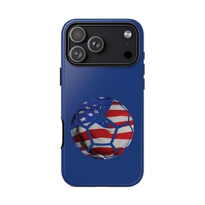 May include: A blue phone case featuring a soccer ball design with the American flag. The soccer ball has a white, red, and blue color scheme. The phone case has a camera module with three lenses.