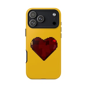 May include: A yellow phone case featuring a pixelated red heart design. The case has a black camera module and black side buttons. The case is designed to fit a smartphone.