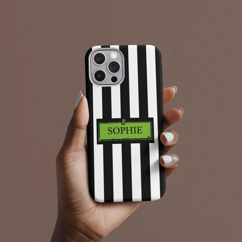 Woman holding a custom name iPhone, Samsung Galaxy, and Google Pixel phone case inspired by Beetlejuice and Wednesday Addams. Black and white striped design with gothic, alternative, and spooky aesthetic. Perfect personalized gift for Halloween, Christmas, or fans of dark fashion and Tim Burton style.