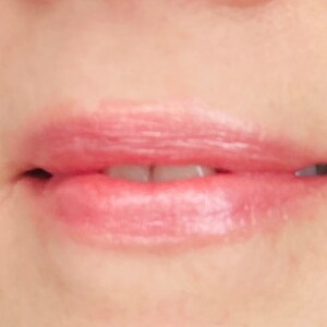 Pu&ograve; includere: Primo piano di labbra che indossano un rossetto rosa chiaro con un leggero luccichio.