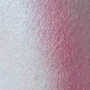 Pu&ograve; includere: Primo piano di un ombretto sfumato con una transizione di colore dal bianco al rosa. L'ombretto ha una finitura scintillante.