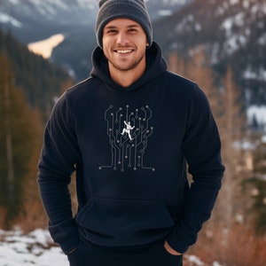 Puede incluir: Una sudadera con capucha azul marino con un gráfico blanco de una persona escalando un circuito impreso. La persona lleva un casco y una mochila. La sudadera tiene una capucha con cordón y un bolsillo canguro.