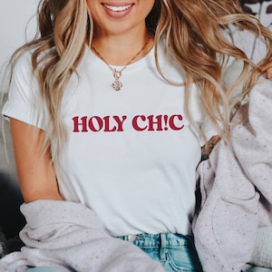 Könnte beinhalten: Weißes T-Shirt mit dem Text "HOLY CH!C" in Rot.