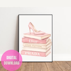 Può includere: Una stampa artistica da parete incorniciata raffigurante una pila di cinque libri in tonalità rosa chiaro e crema. Una singola scarpa con tacco rosa chiaro poggia sopra. I dorsi dei libri mostrano il testo Dior, Louis Vuitton e Prada in lettere bianche e dorate.