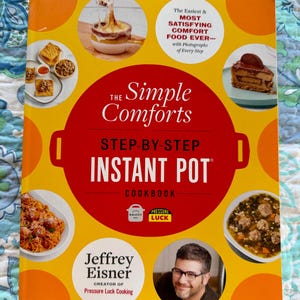 May include: A cookbook titled "The Simple Comforts Step-by-Step Instant Pot Cookbook" with a yellow and red cover. The cover features images of various dishes and the author, Jeffrey Eisner. The text on the cover highlights the ease and satisfaction of comfort food.