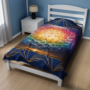 May include: A twin-sized bedspread with a navy blue background and a colorful geometric pattern in the center. The pattern is a rainbow-colored flower of life design with gold accents. The bedspread is made of soft, comfortable fabric.