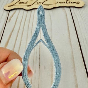 May include: A light blue felt horseshoe charm with a white outline.