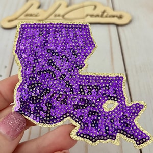 May include: Purple sequin patch shaped like the state of Louisiana with a gold outline.